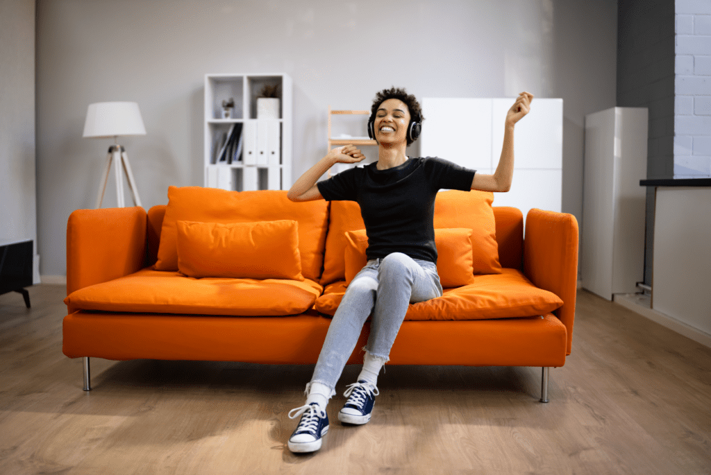 Disabled woman cheering on orange couch in a living room.