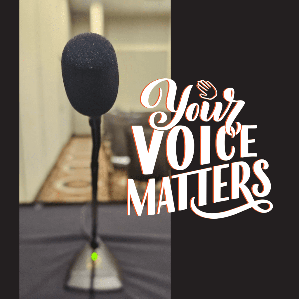 Picture of a microphone on a table in front of a row of chairs with the words, "Your Voice Matters"